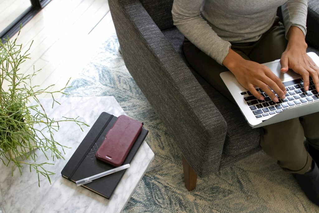 Woman working on laptop in armchair, flexible working
