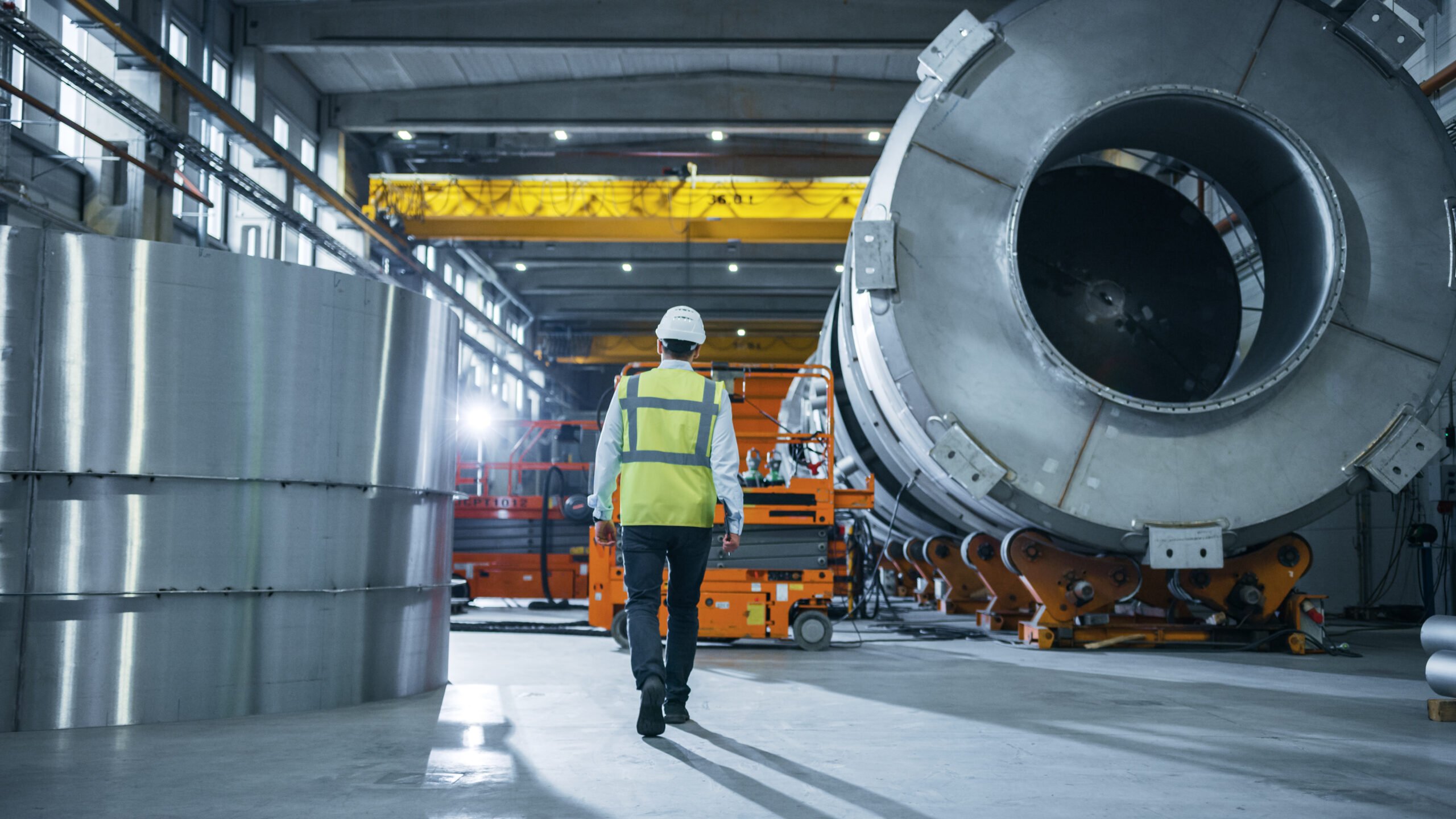 Manufacturing engineer walking through large heavy engineering factory